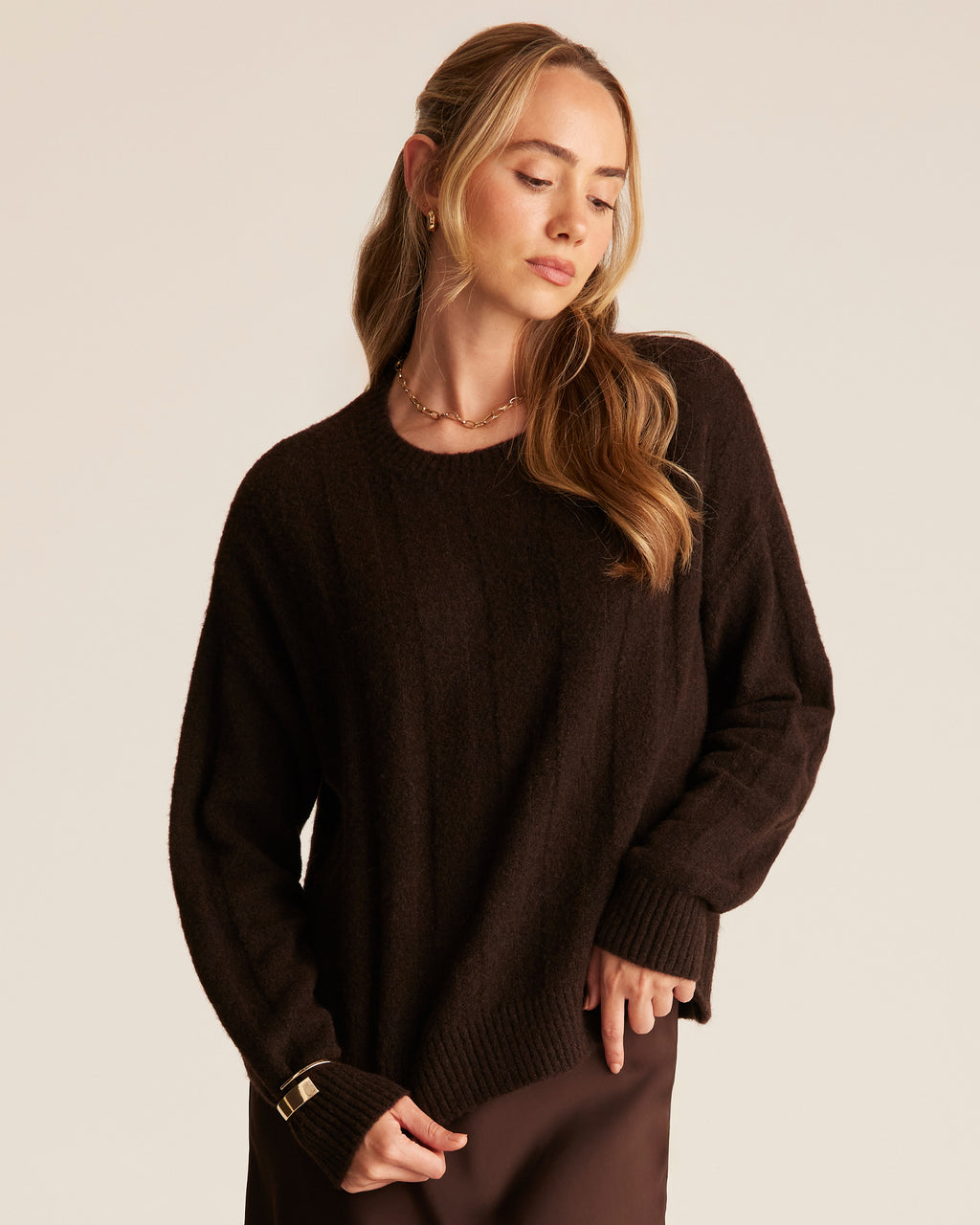 Woman wearing a dark brown sweater against a plain background