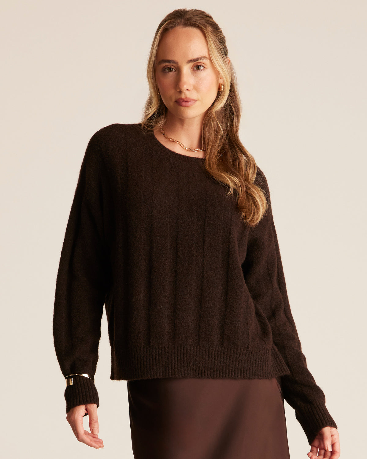 Woman wearing a brown sweater against a plain background